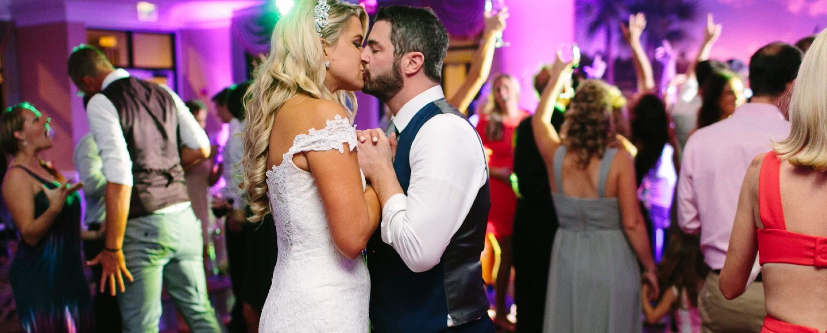 Bride and groom kissing at their wedding reception hosted by band None Other